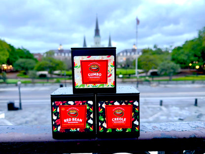 Three packaged food items labeled Creole, Gumbo, and Red Bean, with a view of a historic cityscape in the background.